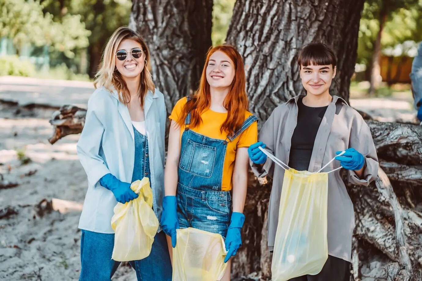Freunde sammeln im Park Müll auf. Sie sammeln den Abfall in einem Müllsack.