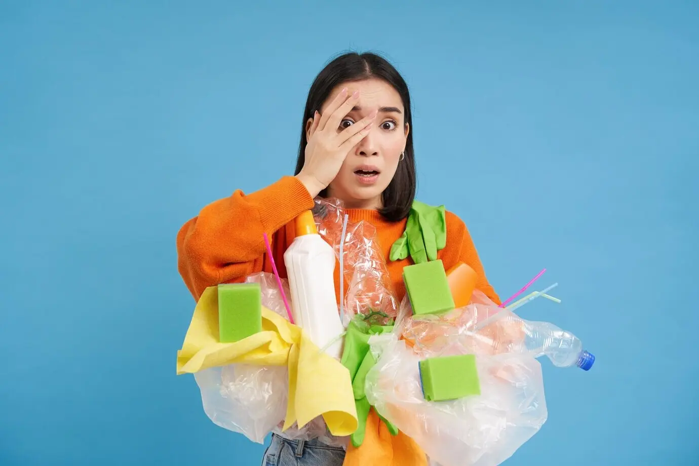 Schockierte asiatische Frau schaut verlegen auf etwas Schreckliches und hält beim Sortieren von Abfall Plastikmüll.
