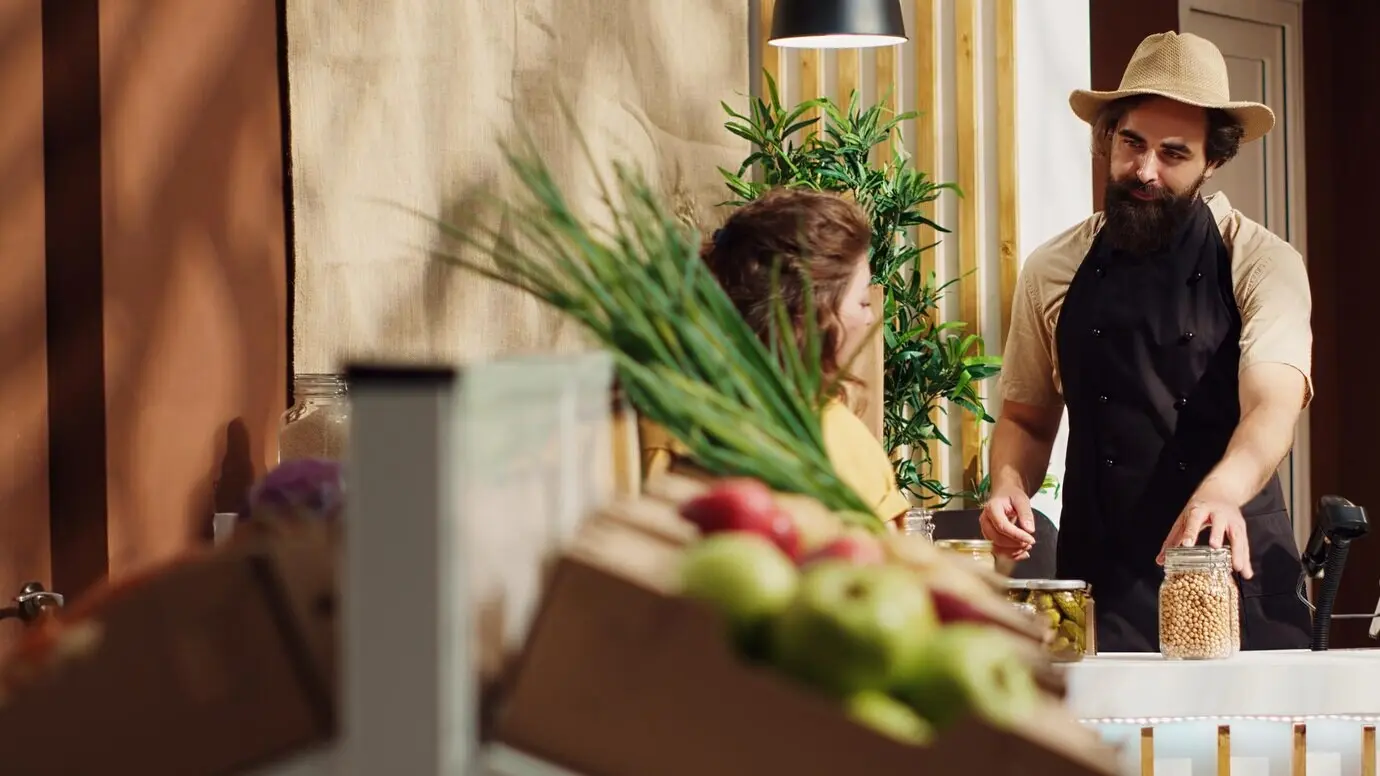 Ein Ladenverkäufer tütet die Lebensmittel eines Kunden ein.